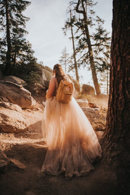 Allison hikes down a rocky trail, her dress covered in dirt but glowing in the sunlight.