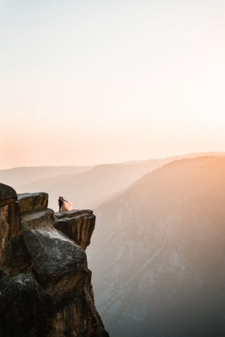 Kevin and Allison stand on a cliff in Yosemite National Park at sunset.
