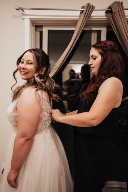 Meghan buttoning the back of Allison's wedding dress in the AirBnB.