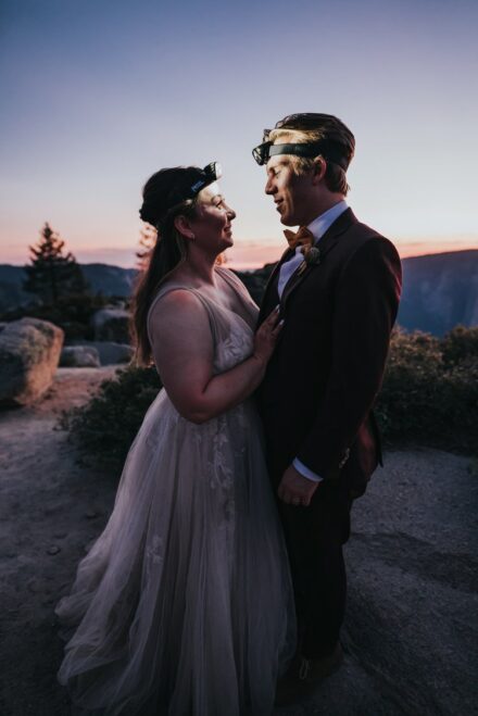 Kevin and Allison wrap their arms around each other, smiling at each other, their faces illuminated by their headlamps.