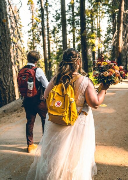 Kevin and Allison hike into Tuolomne Grove in their wedding attire and backpacks.