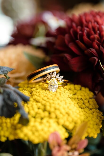 A close up of the wedding rings sitting on top of the bouquet.