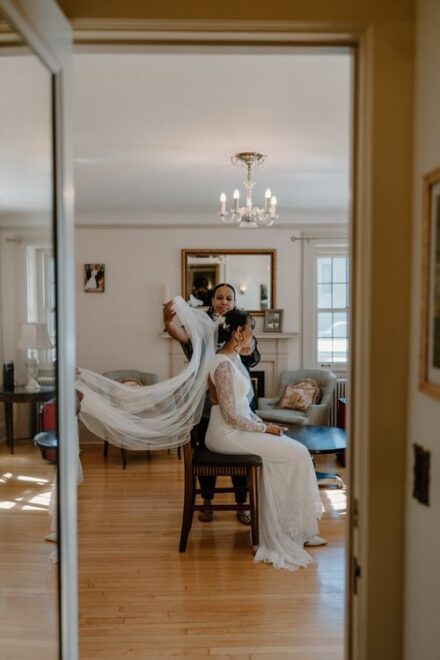 A dramatic shot of Claire's veil being placed in her hair, sweeping out behind her.