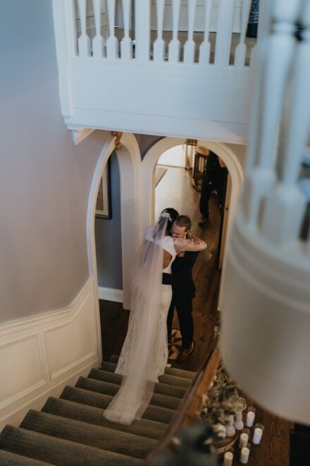 Claire and Tom embrace at the bottom of the stairs during their first look.