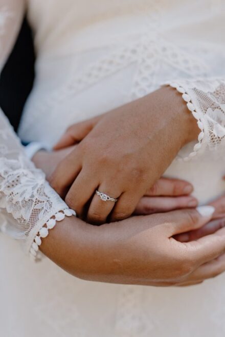 A close up of Claire and Tom's hands wrapped around Claire's waist, focused on Claire's wedding ring.