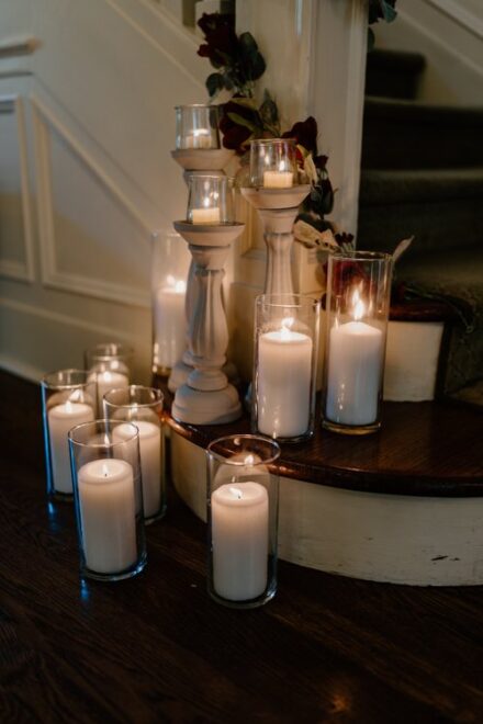 A cluster of lit, white candles at the base of the staircase.