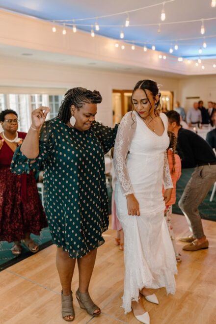 Claire bumps hips with a wedding guest on the dance floor.