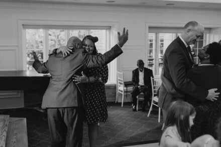Two wedding guests slow dance, dramatically throwing their hands in the air.