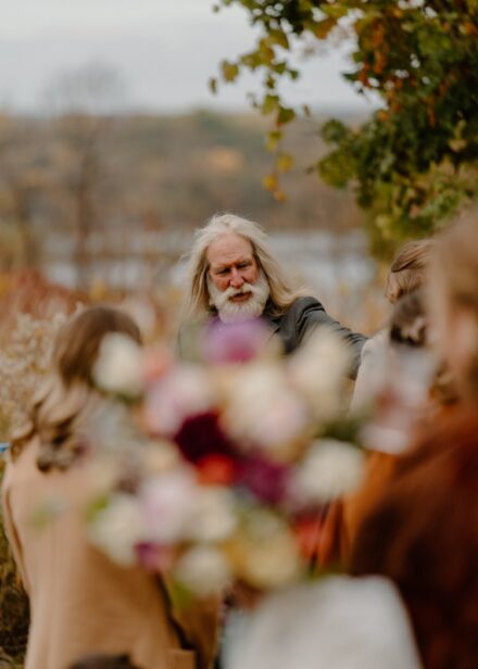 The bride's father in focus behind a blurry bridal bouquet.