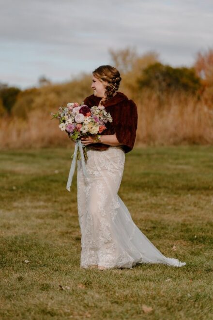 Laura walking down the aisle in her vintage fur jacket, wildflower bridal bouquet in hand.