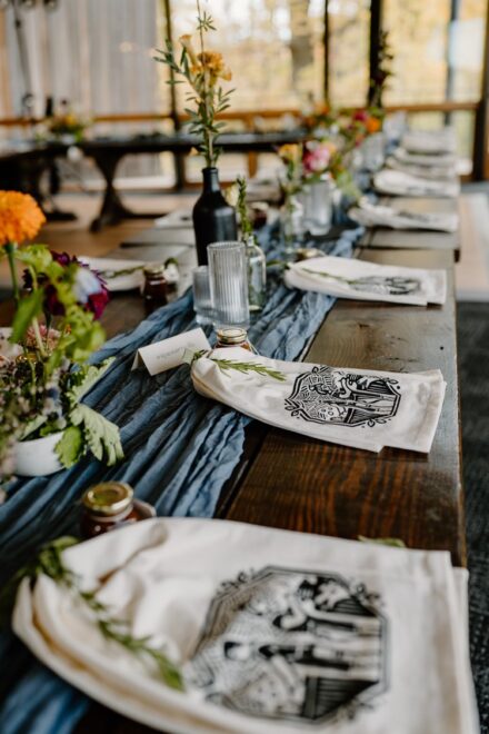 The guest farmhouse table with personalized tea towel place settings and wildflower bud vases.