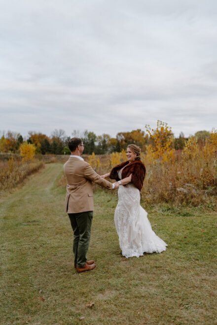 Laura and Joe hold hands and spin in a circle in a field of tall grass.