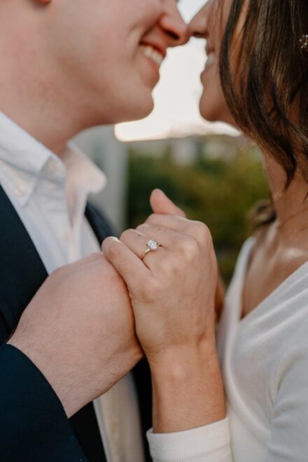 A close up of Ashley and Ehren holding hands, Ashley's engagement ring in focus.