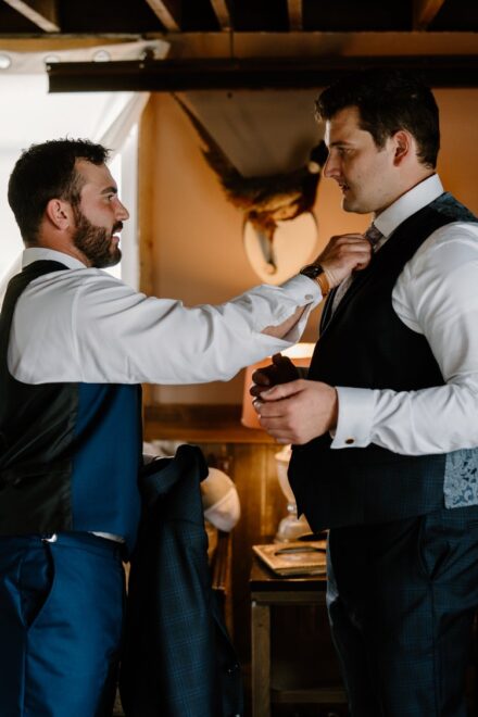 The best man adjust Jake's tie in the groom's getting ready suite.