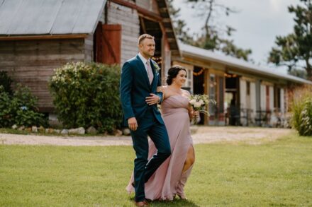 A bridesmaid in a dusty rose dress walking down the aisle with a groomsman in a blue suit.