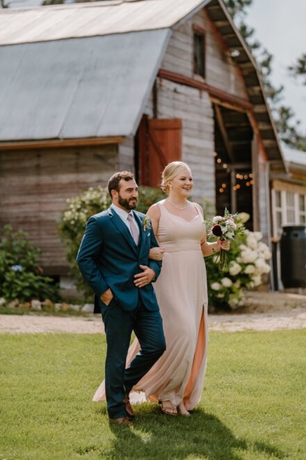 A blonde bridesmaid in a baby pink dress walking down the aisle with a groomsman in a blue suit.