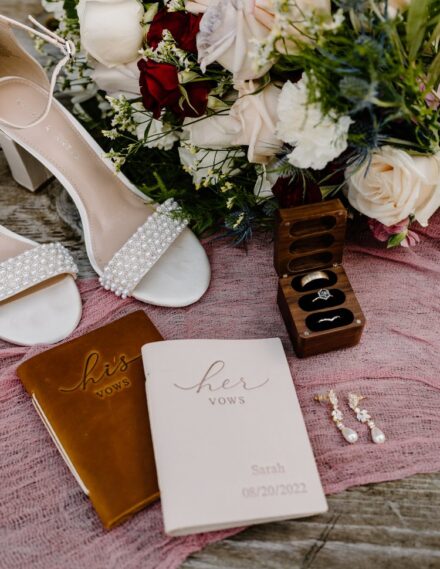 Pearl covered heels, leather bound his and her's vow books, diamond earrings, and a ring box holding the wedding rings.