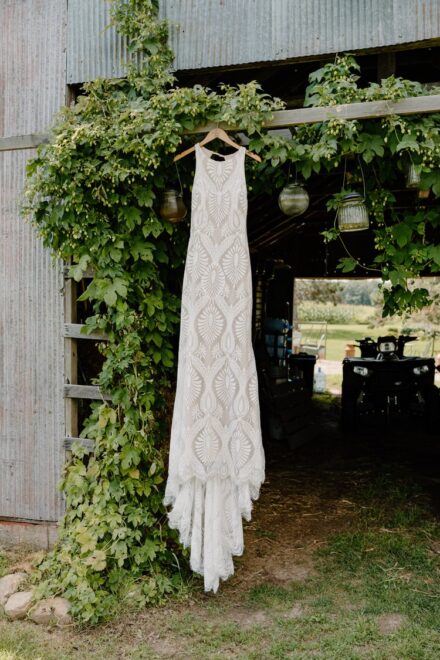 The bride's lace covered wedding dress hanging on an ivy covered eave.