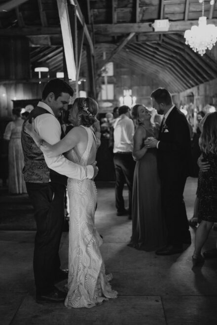 Sarah and Jake dance closely together, with other couples dancing together during a slow dance at their reception.