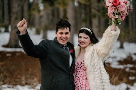 A couple cheering with their arms up in the air after their elopement.
