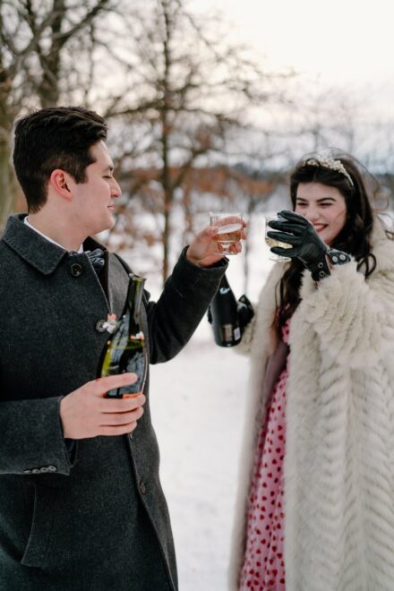 A bride and groom drinking champagne after their winter elopement.