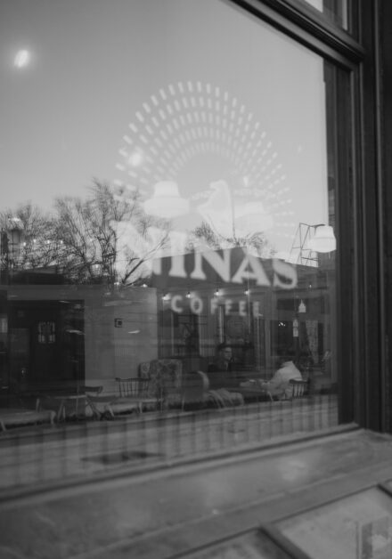 Andy and Marko partially visible behind the Nina's Coffee Cafe sign window taken from outside of the coffee shop.
