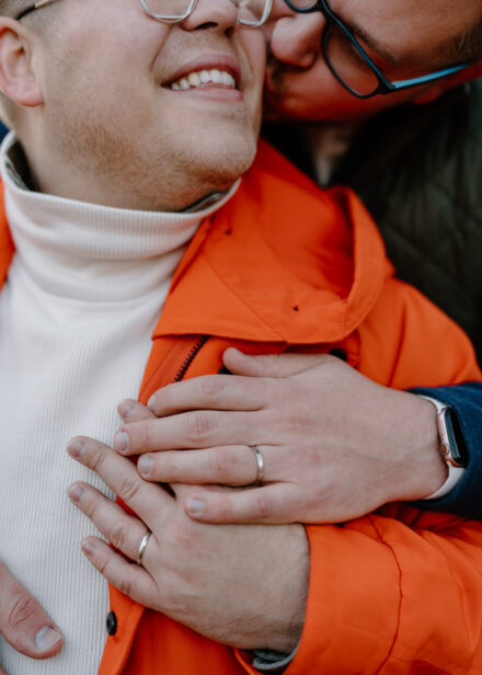 A close up of Andy and Marko holding hands with their engagement rings.