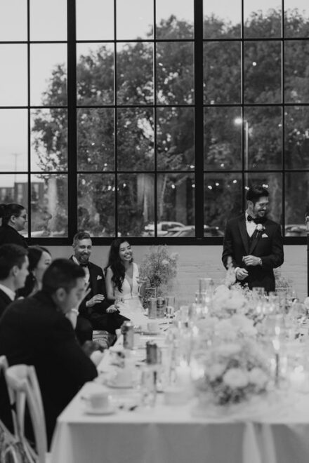 The best man and wedding couple laughing during speeches.