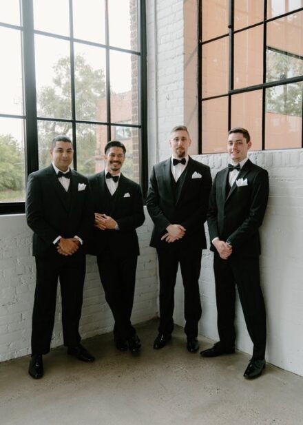 Groomsmen standing in a corner, smiling at the camera at The Whim in Minneapolis.