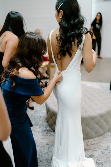 A bride's older sister zipping up her wedding dress.