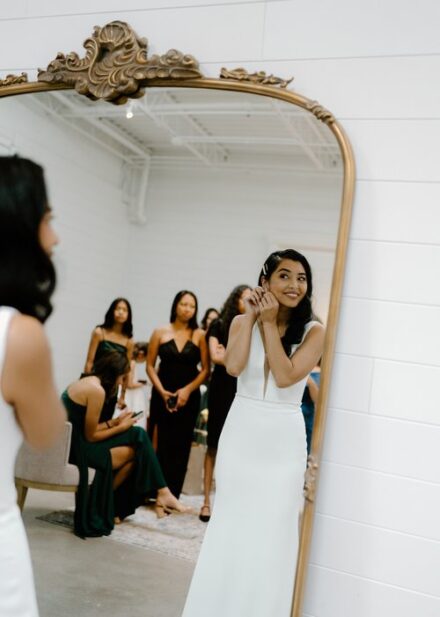 A bride putting on her earrings in front of a mirror at The Whim.