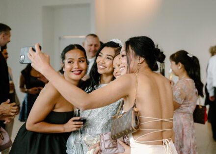 The bride in Khmer wedding attire posing for a selfie with wedding guests.