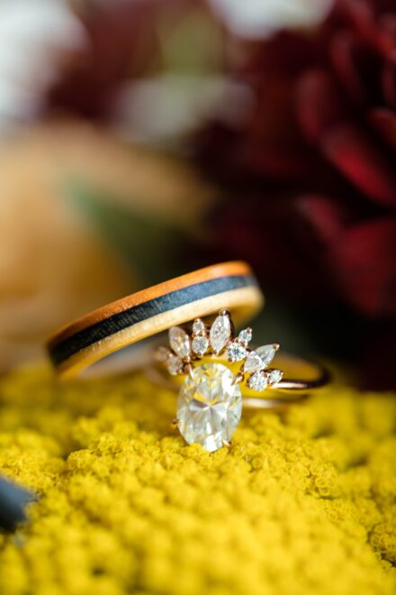 Two wedding bands and an engagement ring sitting on top of a yellow flower.