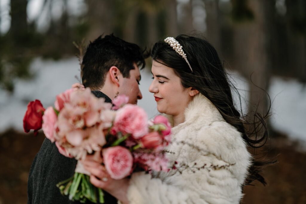 A couple embracing after their elopement in Stillwater Minnesota holding a bright pink bouquet.