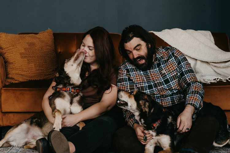 My husband and I with our two Australian Shepherd and Lab mix dogs, one licking my face.