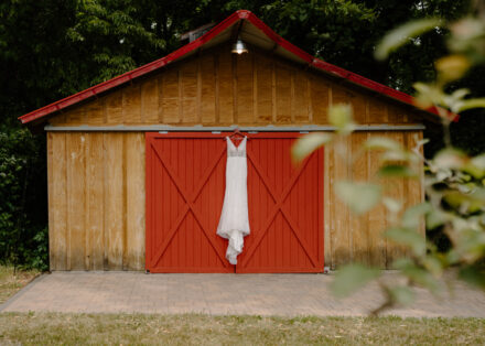 Anna's wedding dress hangs outside the red door of her getting ready cabin at Minnetonka Orchard.