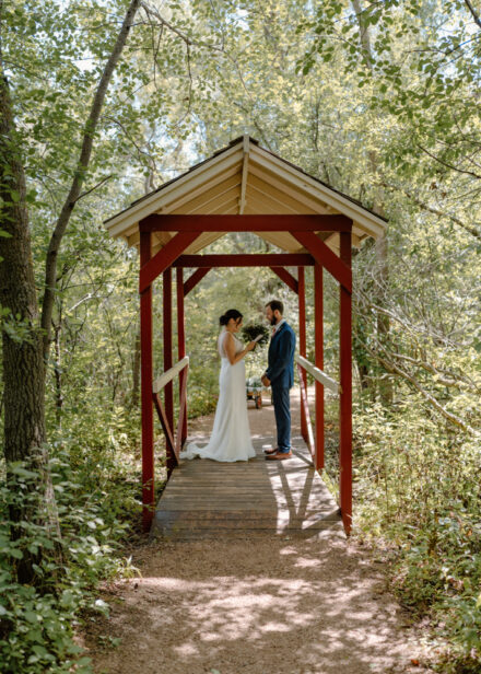 Anna and Jason read their private vows under a red, covered bridge.