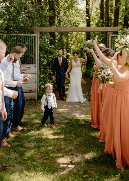 A ring bearer walks between the wedding party in two separate lines.