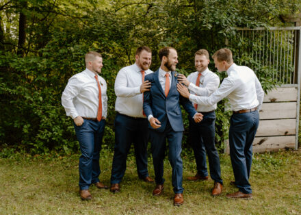 The groomsmen hype up the groom, patting him on the back.