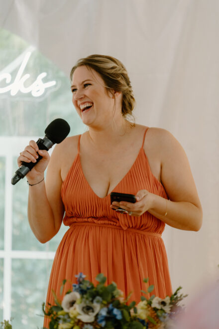 The maid of honor laughs during her speech.