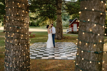 Anna and Jason dance together underneath twinkle lights outside.