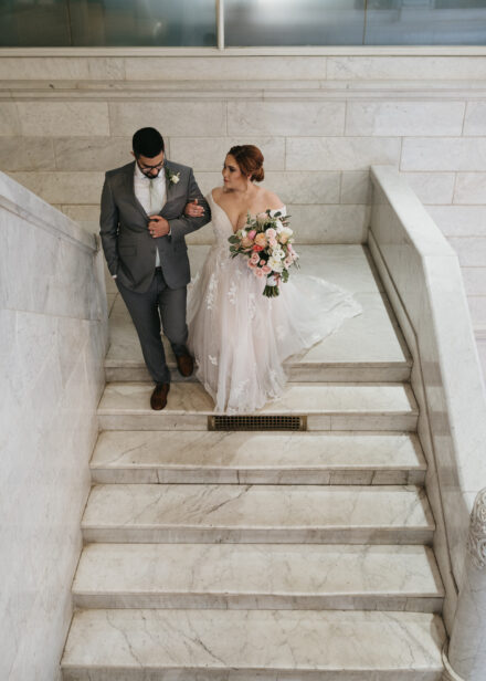 Connie & Taysir walk together down the white marble staircase.