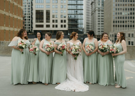 Connie and her bridesmaids smile and laugh together on the rooftop.