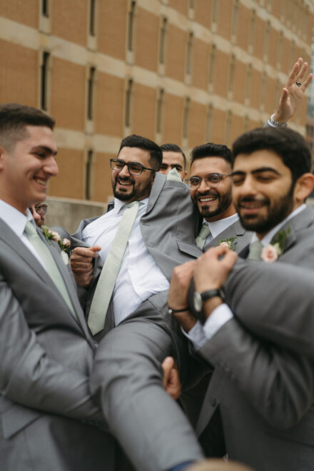 Taysir's groomsmen attempt to pick him up, but mostly drop him.