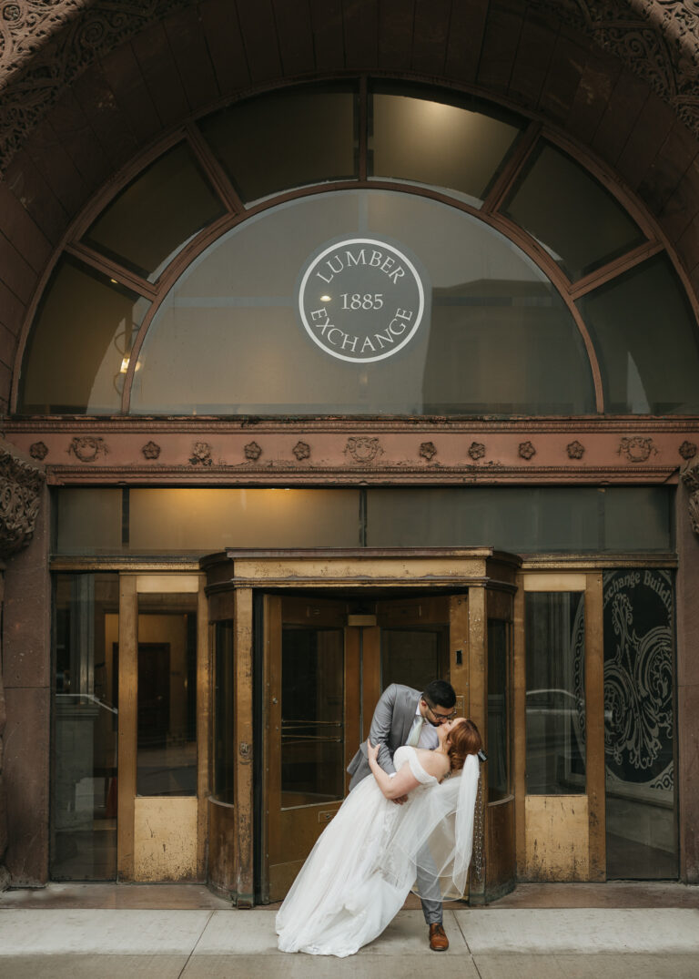 The couple kisses under the Lumber Exchange Center sign.