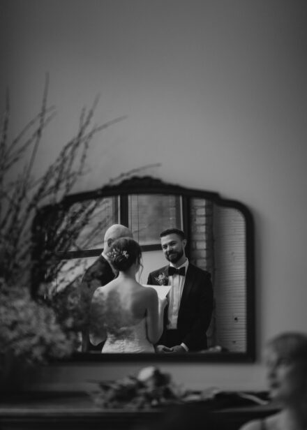 A reflection of Matt smiling lovingly at Beth in the mirror during their ceremony.