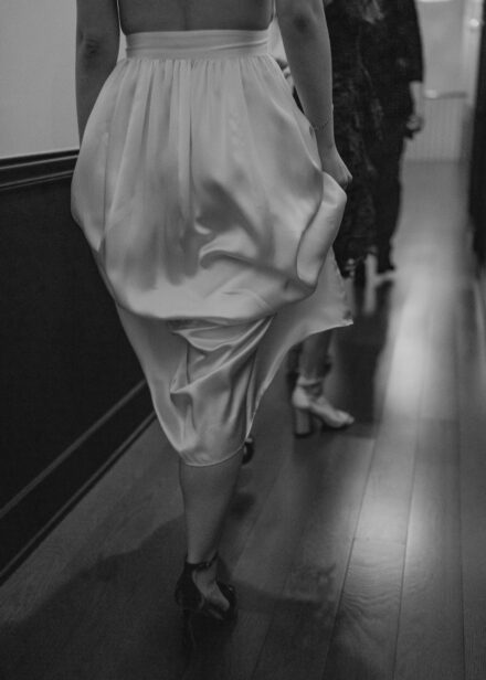 Beth holds her skirt as her friends walk single file down the narrow hallway.