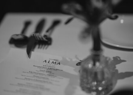 A black and white close up of the evening's menu covered in shadows from the table's center piece.