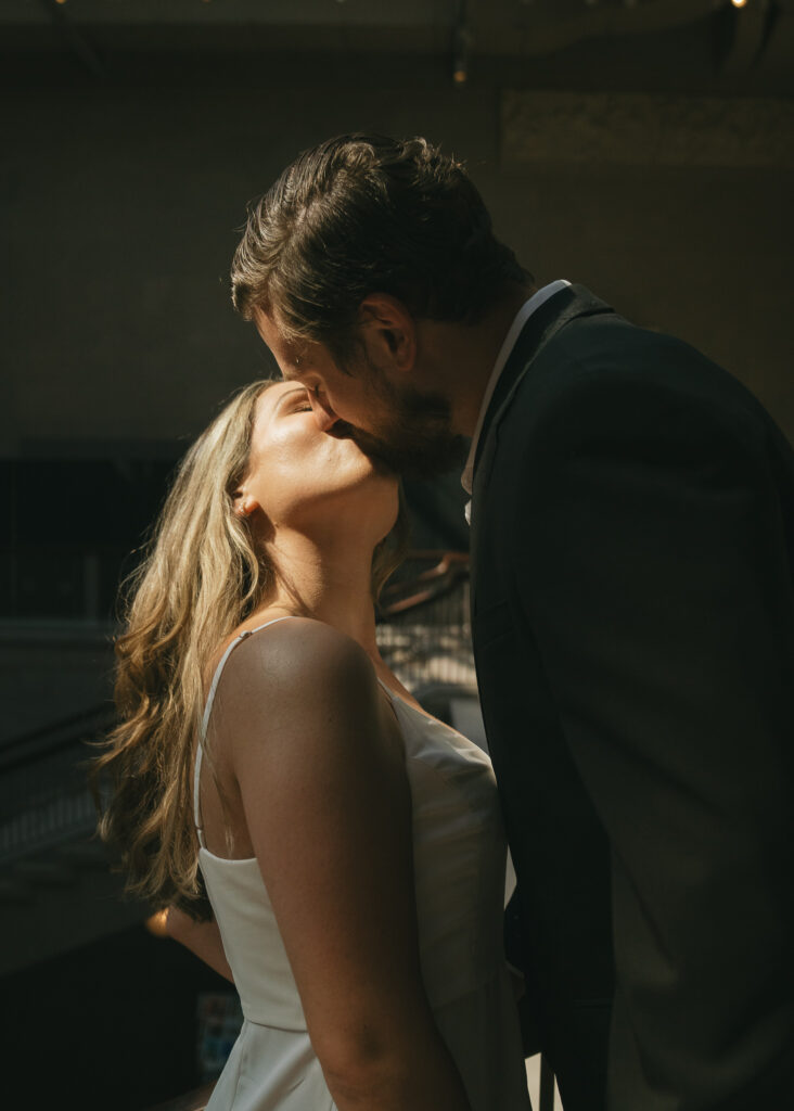 The couple kisses, the sunlight hitting the sides of their faces.