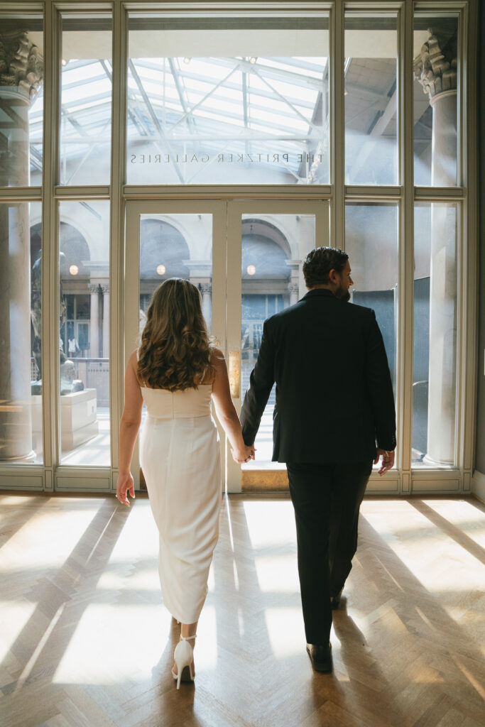 The couple walks out of a gallery and into the light-filled balcony.